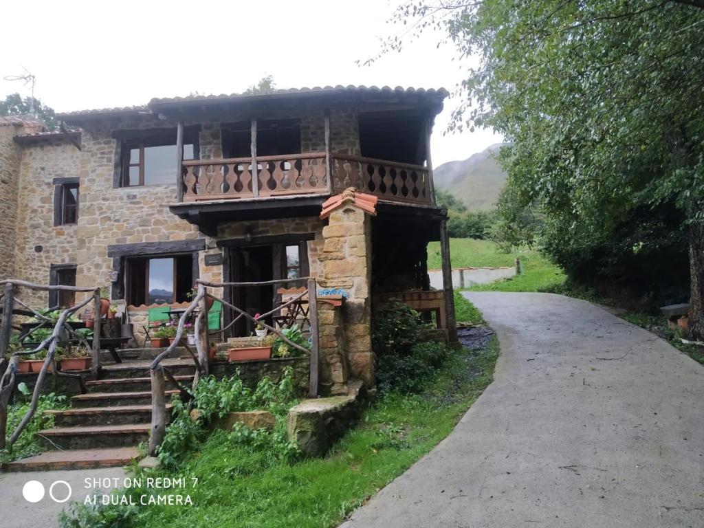 uma casa de pedra com uma varanda ao lado de uma estrada em Albergue De Soba em Lavín