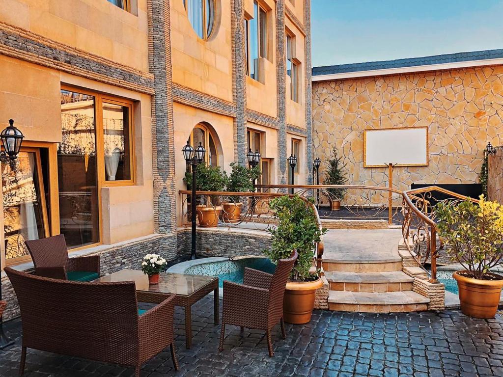 eine Terrasse mit einem Tisch und Stühlen sowie ein Gebäude in der Unterkunft Bayil Breeze Hotel & Restaurant in Baku