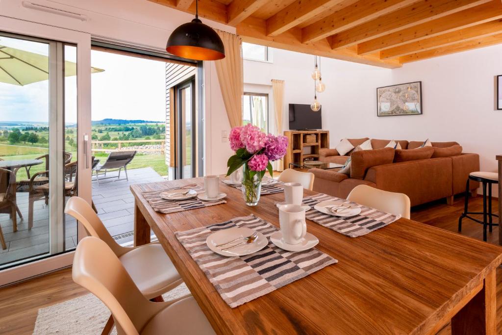 uma sala de jantar e sala de estar com uma mesa de madeira e cadeiras em Ferienhäuser Immenhöfe em Donaueschingen