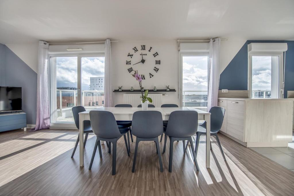 a dining room with a table and chairs and a clock at Appartements de 2 ou 3 chambres à 40 minutes de Paris in Evry-Courcouronnes