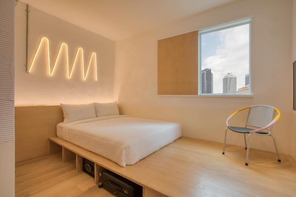 um quarto com uma cama e uma cadeira em MoMo's Kuala Lumpur em Kuala Lumpur