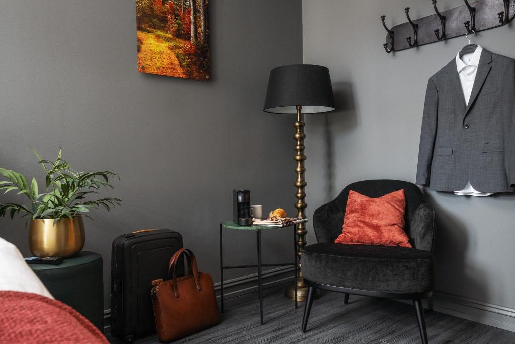 a room with a chair and a suit hanging on a wall at Hotel Filip in Oslo