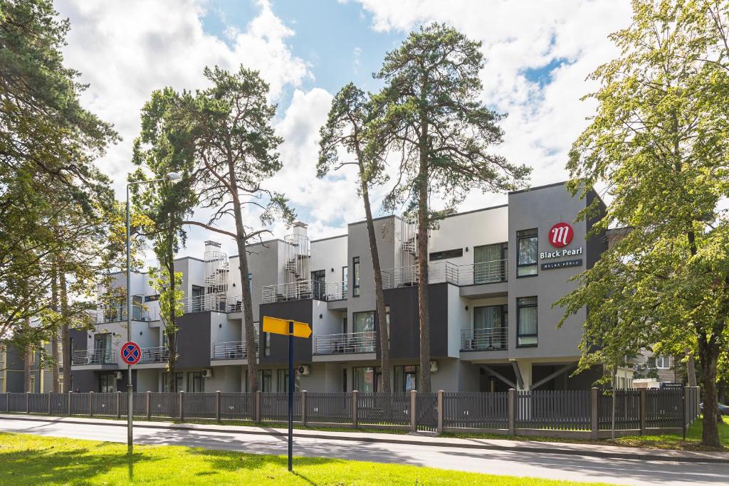 un edificio de apartamentos con una valla y árboles en Black Pearl Apartments en Jūrmala