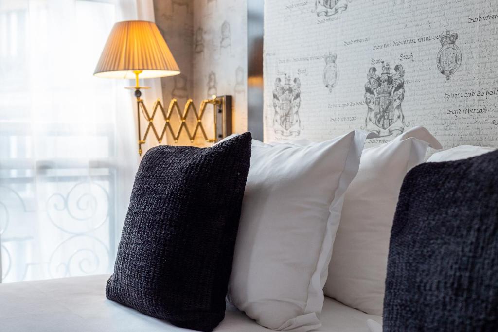 two pillows sitting on a bed with a lamp at Villa Lutèce Port Royal in Paris