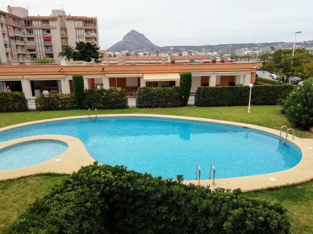 une grande piscine bleue devant un immeuble dans l'établissement Apartamento Playa Jávea, à Jávea