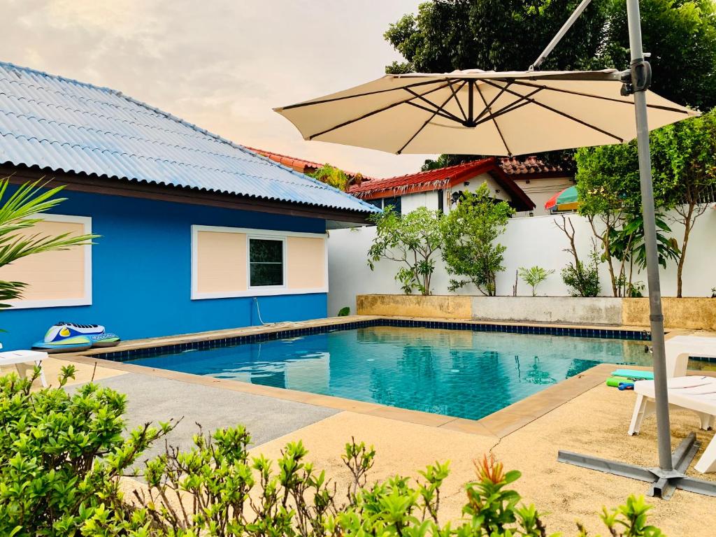 a swimming pool with an umbrella next to a house at 2 bedroom bungalow Nai Harn 4 Resort in Ban Suan