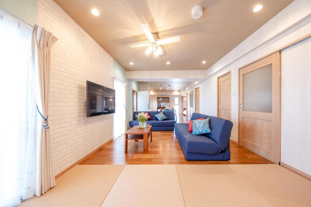 a living room with two blue couches and a tv at Hotel Haabesu Okinawa in Urazoe