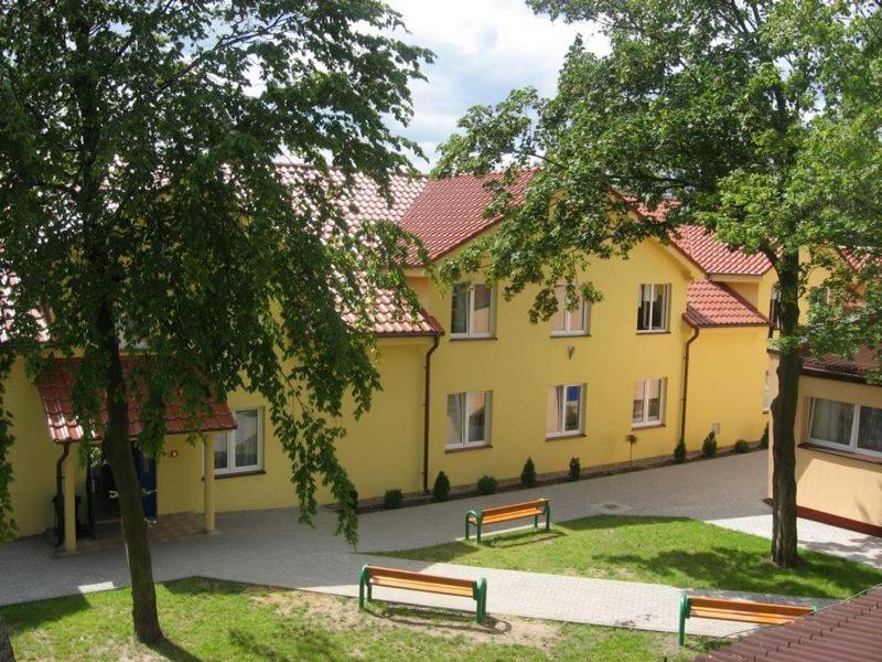 dos bancos frente a un edificio amarillo en Ośrodek Wczasowo - Kolonijny Słoneczko, en Łeba