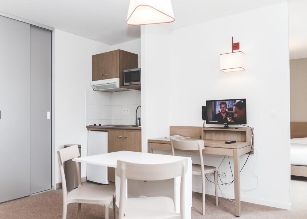 uma cozinha e sala de jantar com mesa e cadeiras em Terres de France - Appart'Hotel Quimper Bretagne em Quimper