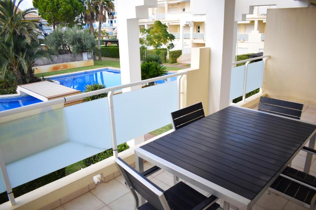 balcón con mesa y sillas y piscina en Anacasa Vora Golf 3 Playa Rabdells DUP3027, en Oliva