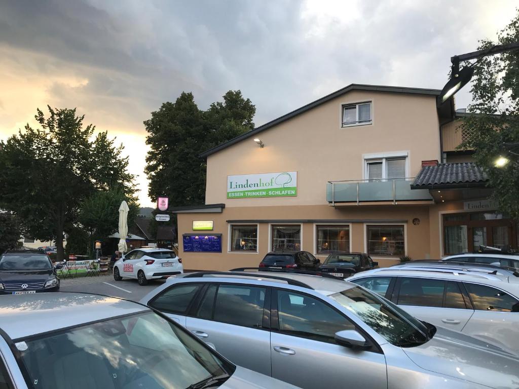 a building with cars parked in a parking lot at Gasthof-Pension Lindenhof in Unterburg am Klopeiner See