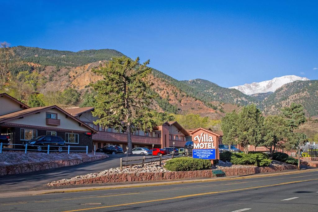 a motel sign on the side of a street with mountains at Villa Motel at Manitou Springs in Manitou Springs