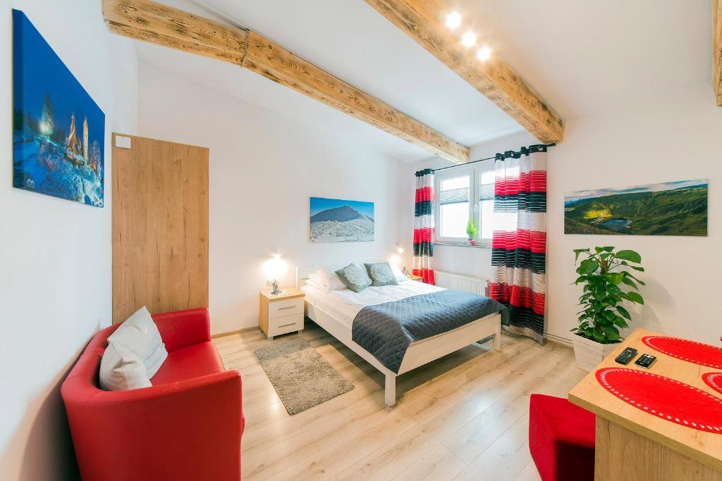 a bedroom with a bed and a red chair at Apartamenty i Pokoje Karpacz - centrum Karpacza, parking w cenie! in Karpacz
