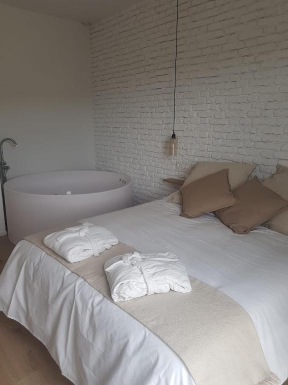 Un dormitorio con una cama blanca con toallas. en Dos Alas Rojas, casa con jacuzzi para dos personas en Mélida