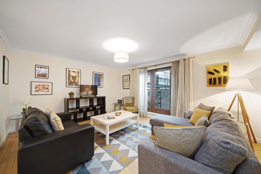 ein Wohnzimmer mit einem Sofa und einem Tisch in der Unterkunft 2 Bed Chic Apartment near Shoreditch & Liverpool St FREE WIFI & PARKING by City Stay Aparts London in London