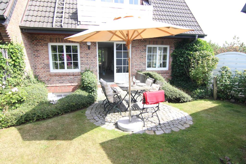 a table and chairs under an umbrella in a yard at Ferienhaus Ekke Nekkeppen2 in Westerland (Sylt)