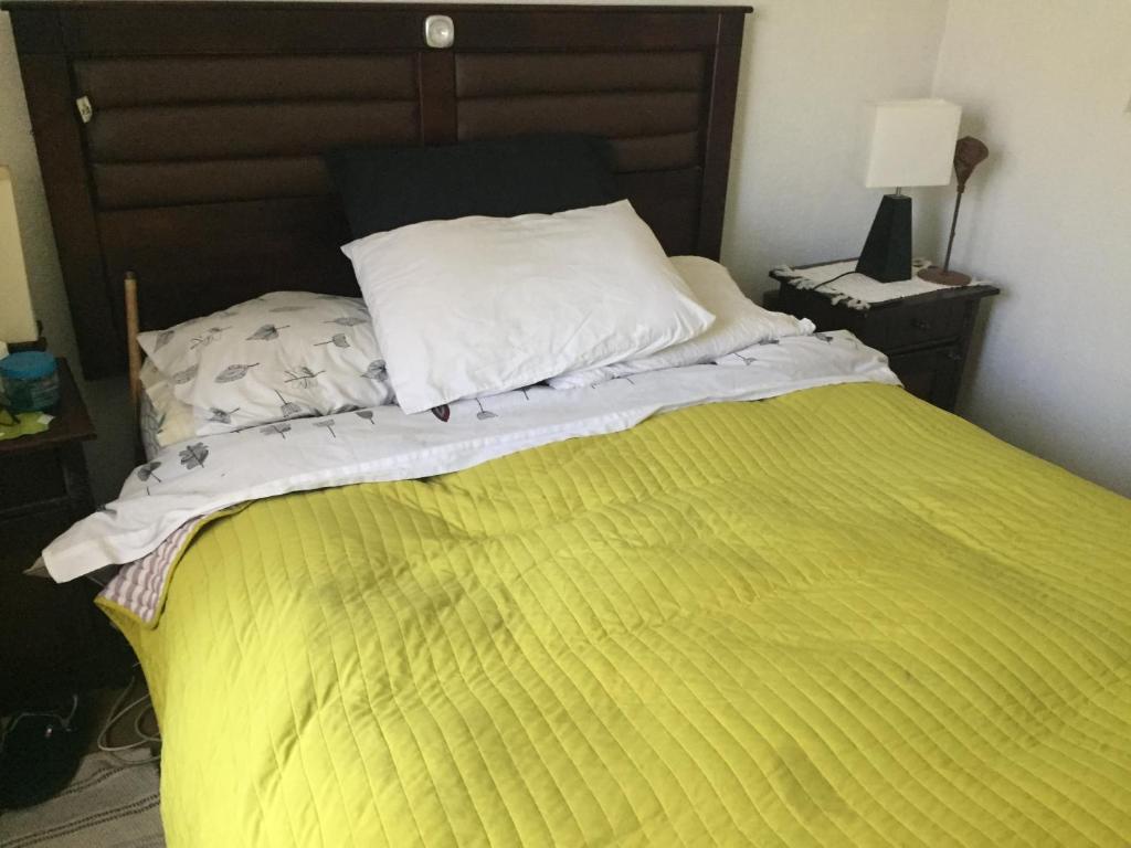 a bed with a yellow comforter and a pillow at habitaciones exclusivas in Curicó