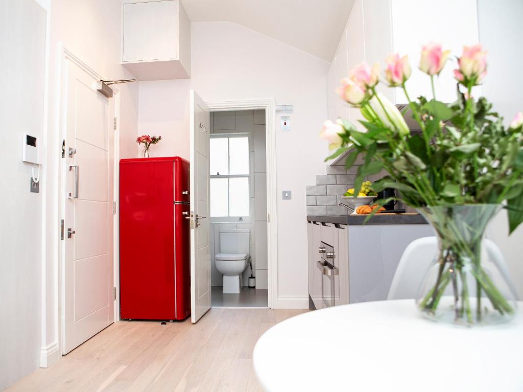 a kitchen with a red refrigerator and a table with flowers at Carnaby Studios by Indigo Flats in London