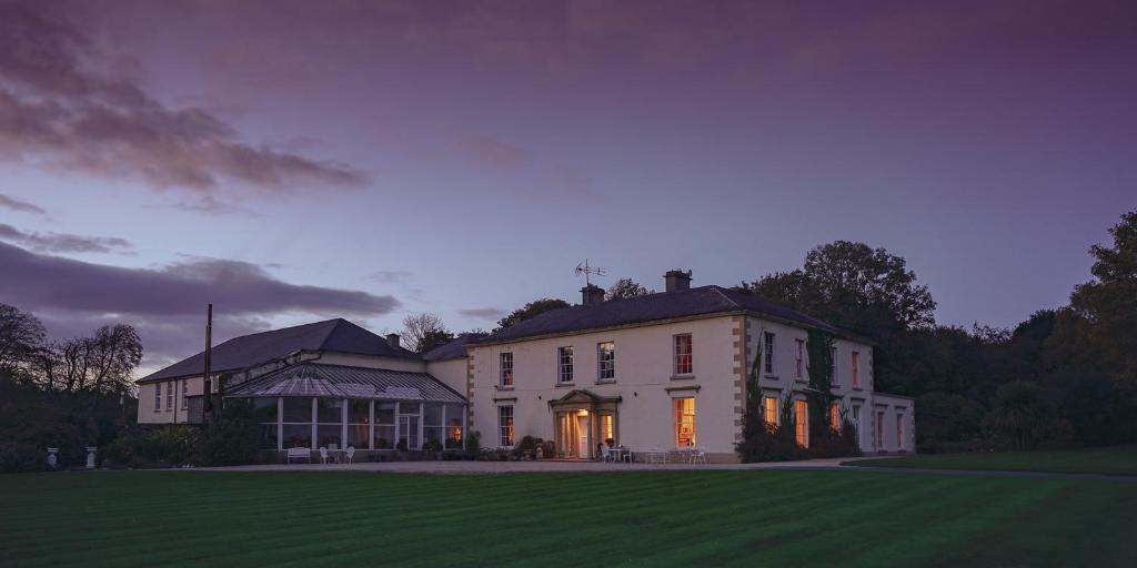 a large white house with a lawn at night at Castle Grove Country House Hotel in Letterkenny