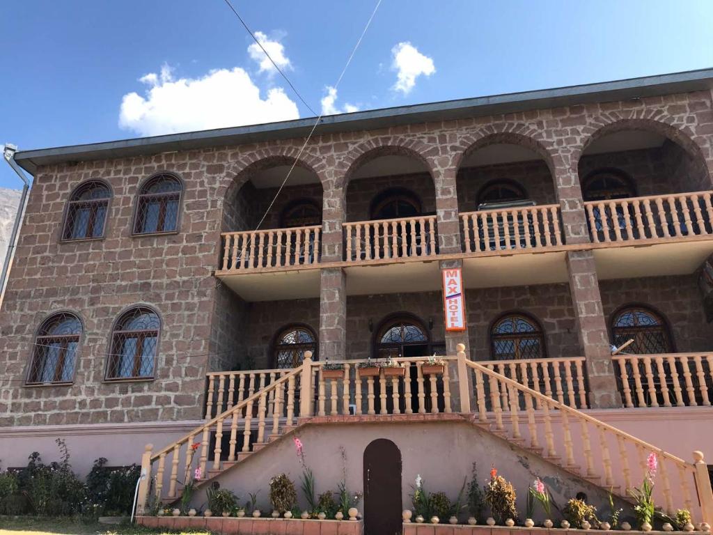 a large brick building with a staircase in front of it at Max Hotel Gogi Alibegashvili in Stepantsminda