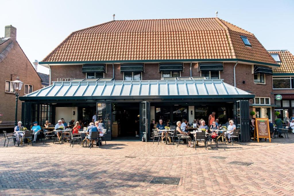 een groep mensen die aan tafels buiten een gebouw zitten bij Hotel Restaurant de Jong in Nes