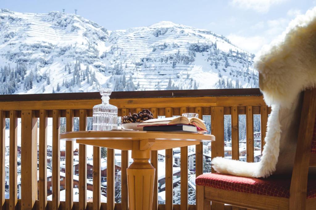 a table on a balcony with a snow covered mountain at hotel & chalet madlochBlick in Lech am Arlberg