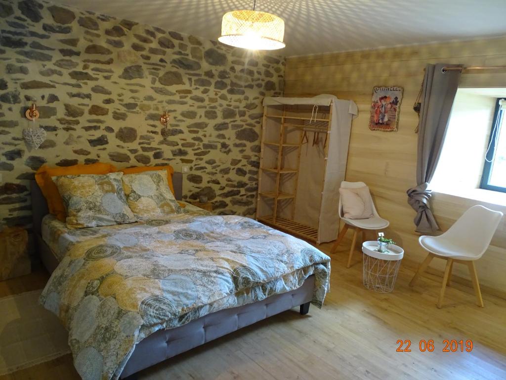 1 dormitorio con cama y pared de piedra en L étable au naturel, en Mauriac