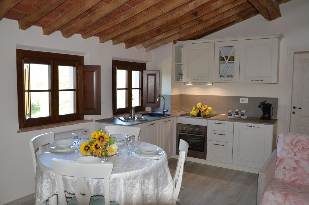 een keuken met een tafel met stoelen en een eetkamer bij Le Bozze "Il Frantoio" con piscina, Wi-Fi, posto auto in Castagneto Carducci