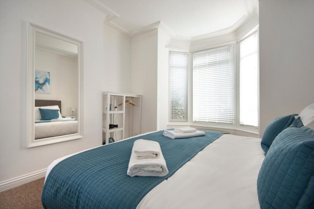 a bedroom with a large bed with two towels on it at Francis Hollow - Modern 2 double bedroom garden apartment in Southsea, Portsmouth in Portsmouth