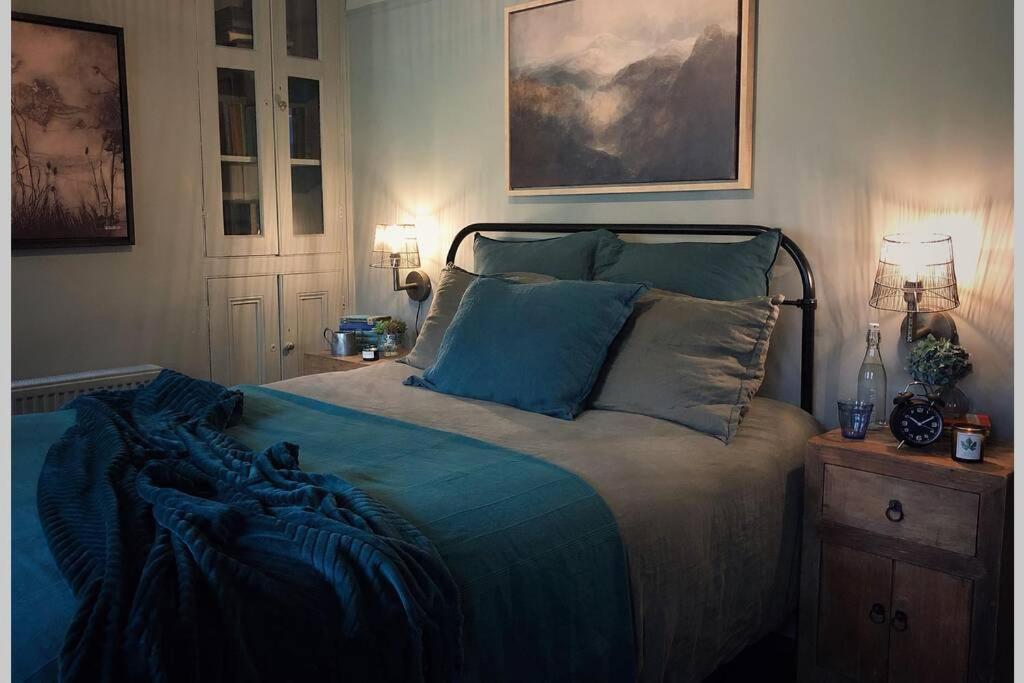 a bedroom with a bed with blue sheets and pillows at CELYN - SNOWDONIA COTTAGE in Caernarfon