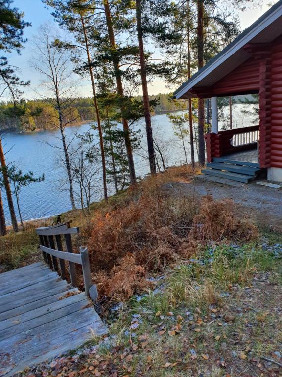 a bench in front of a cabin with a view of a lake at Pankkotupa 66 "13B" in Savonlinna