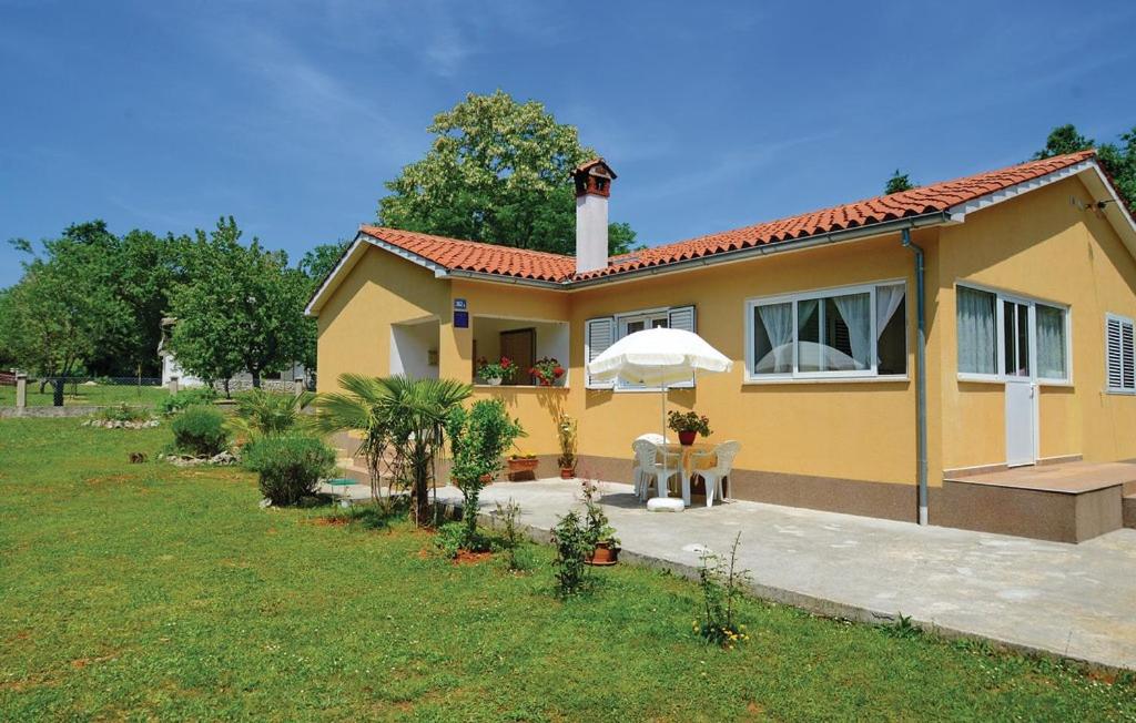 a small yellow house with a table and an umbrella at Kuća za odmor Mendez in Labin
