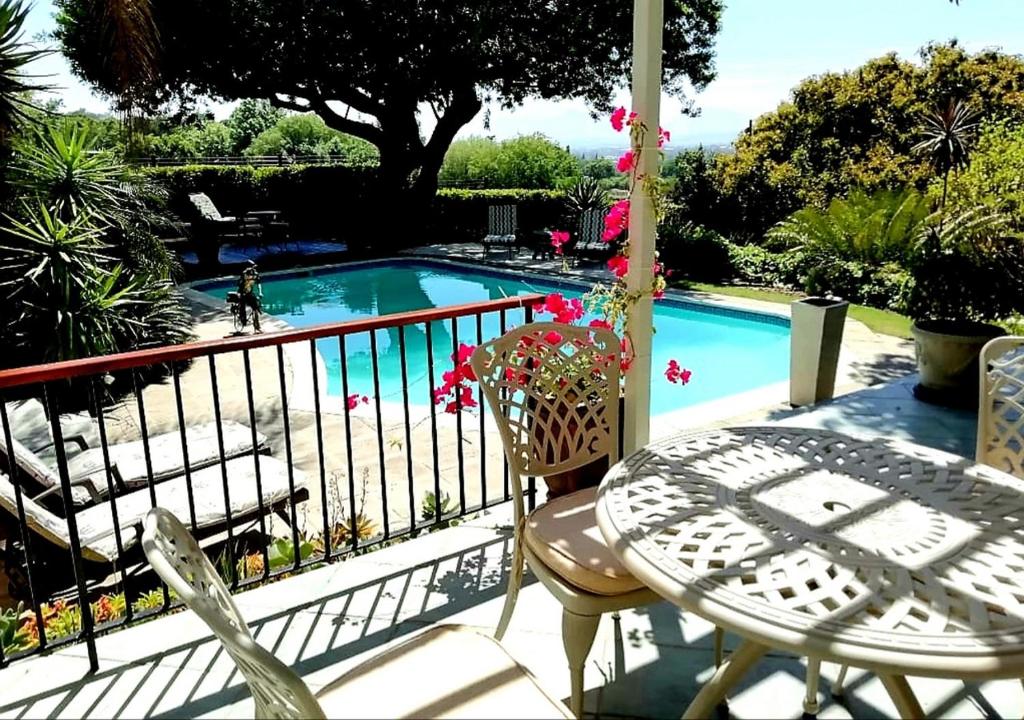 a balcony with a table and chairs and a swimming pool at De Wingerd Wijnland Lodge in Paarl