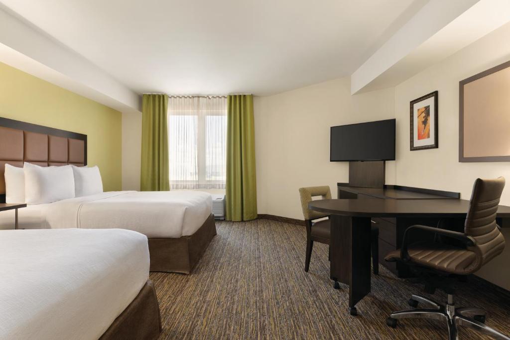 a hotel room with two beds and a desk at Park Inn by Radisson, Calgary Airport North, AB in Calgary