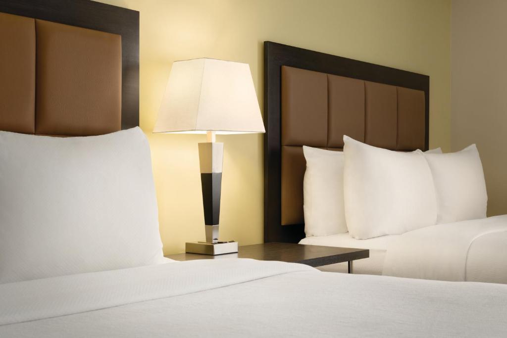 a hotel room with two beds and a lamp at Park Inn by Radisson, Calgary Airport North, AB in Calgary