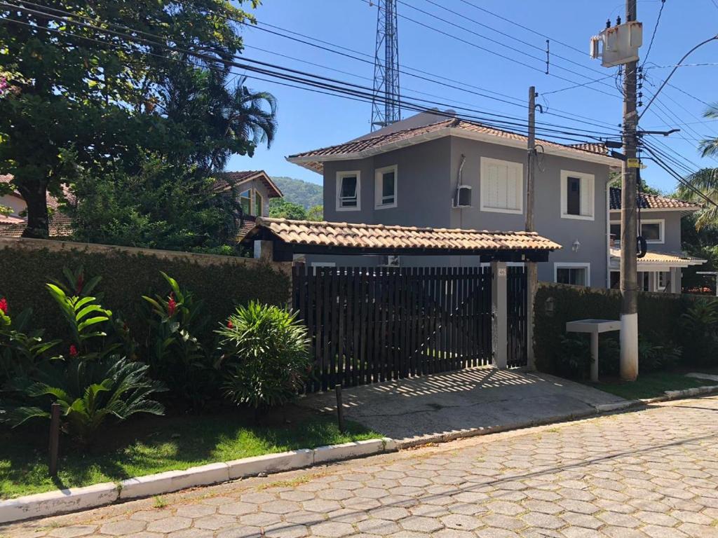 una casa blanca con una puerta negra delante en Lar Doce Lar Toque Toque Grande en São Sebastião