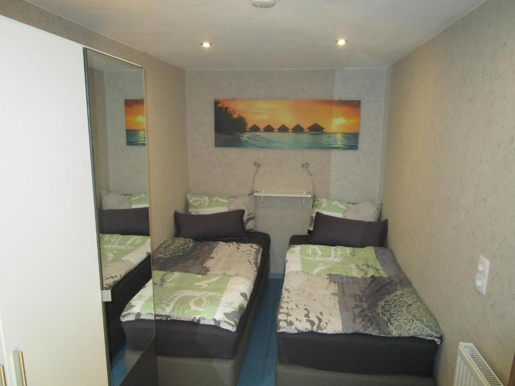 two beds in a small room with a mirror at Übernachtung an der A2 in Braunschweig