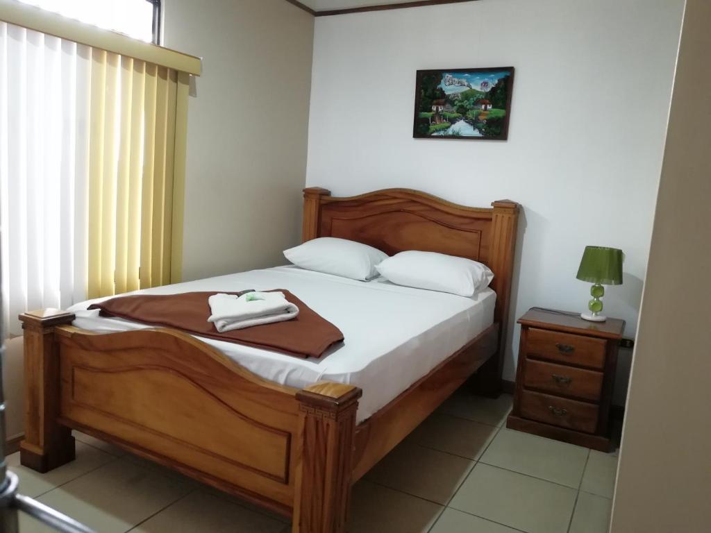 1 dormitorio con cama con marco de madera y mesa en Hospedaje Yaldai, en Turrialba