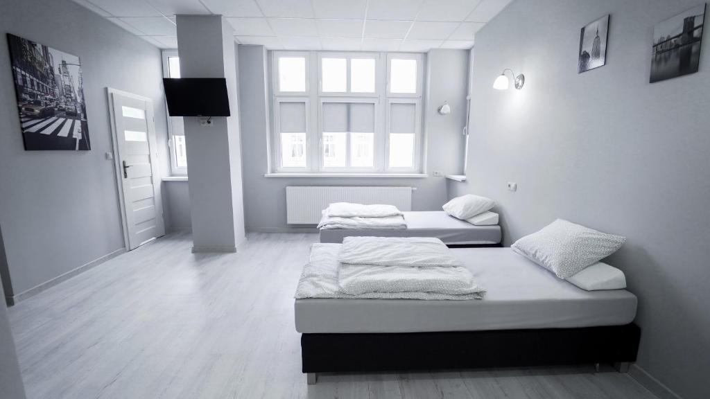 a room with two beds and a television in it at Rooms Śląska in Bydgoszcz