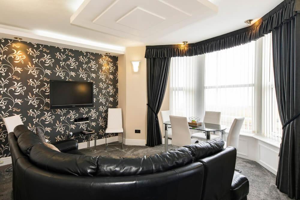 a living room with a leather couch and a television at Burbage Holiday Lodge Apartment 3 in Blackpool