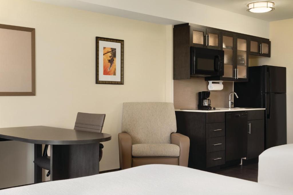 a hotel room with a kitchen and a table and a room at Park Inn by Radisson, Calgary Airport North, AB in Calgary