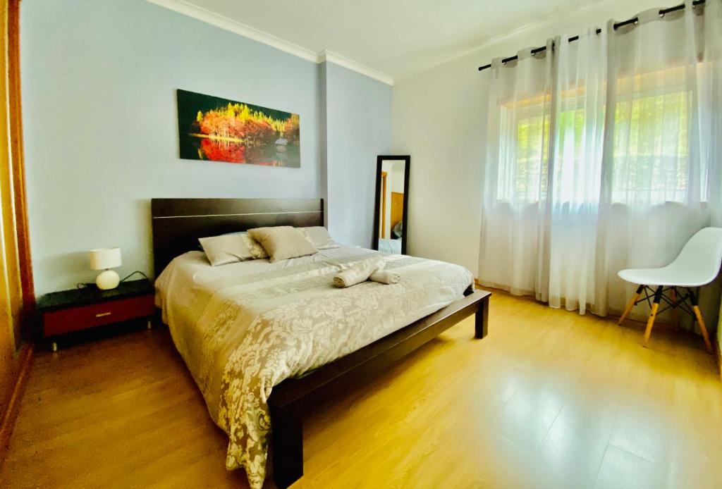 um quarto com uma cama e uma cadeira em Apartamento Coselhas Coimbra em Coimbra
