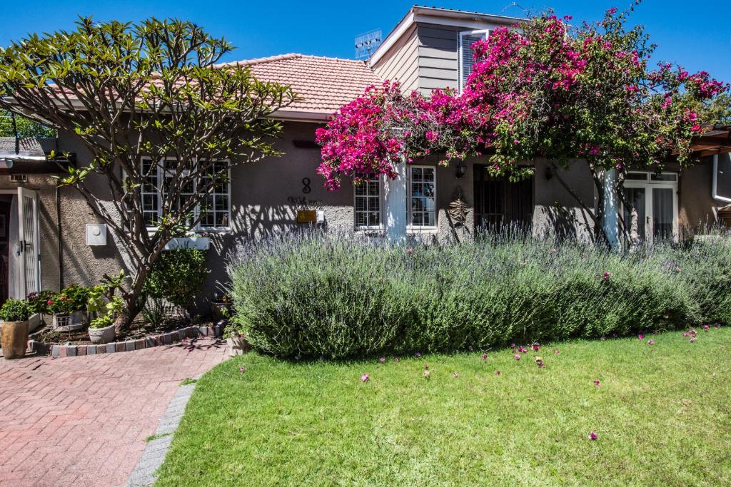 ein Haus mit rosa Blumen im Hof in der Unterkunft Greenlawns B&B in Kapstadt