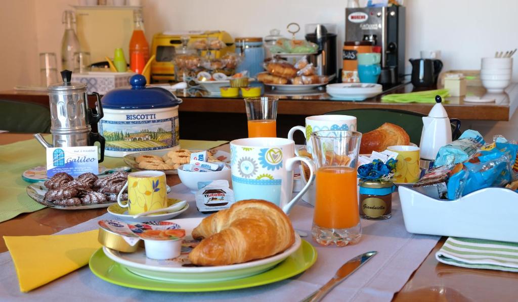 einen Tisch mit einem Frühstück mit Croissants und Orangensaft in der Unterkunft B&B Galileo in Neapel