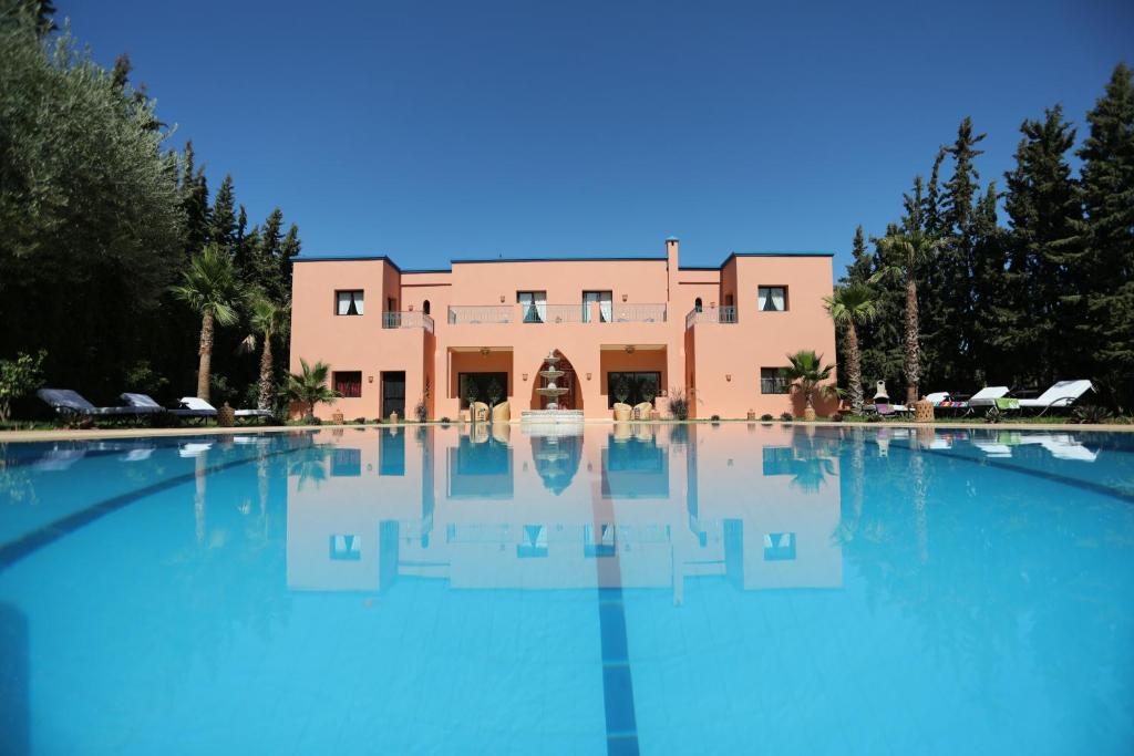 a large swimming pool with a building in the background at Tiguemine Sarah in Marrakech