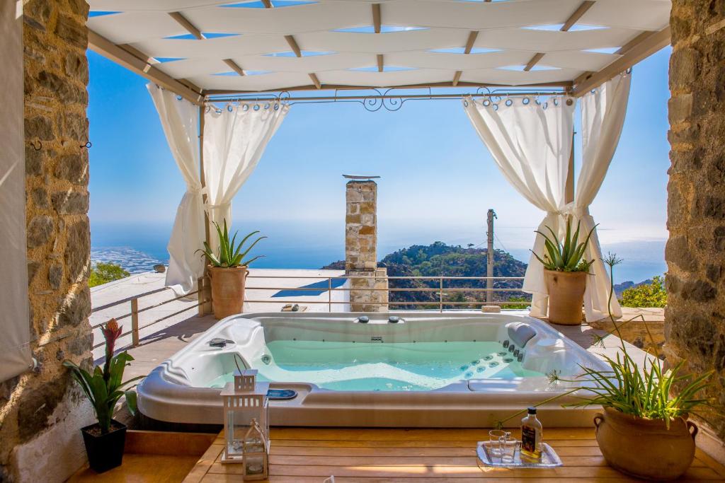 een hot tub op een patio met uitzicht op de oceaan bij Dorovinis Country Houses in Anatolí