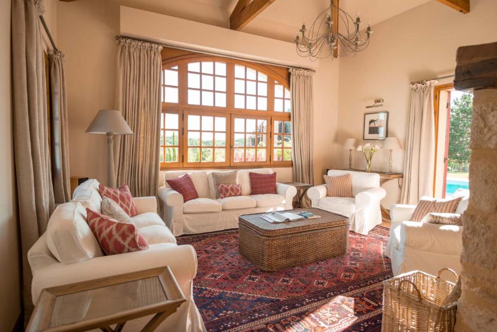 un salon avec des meubles blancs et une grande fenêtre dans l'établissement La Maison, à Villeneuve-de-Duras