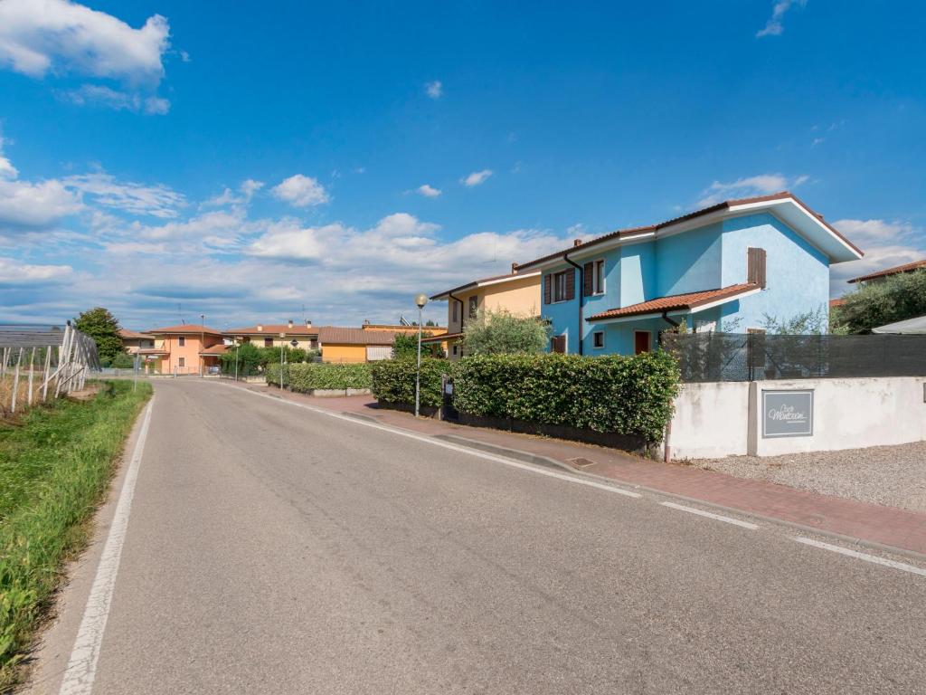 Droga z niebieskim domem na boku w obiekcie Appartamento Bella Cora w mieście Lazise