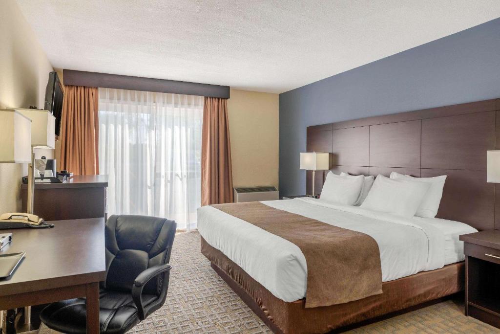 a hotel room with a large bed and a desk at Quality Inn & Suites in Bathurst