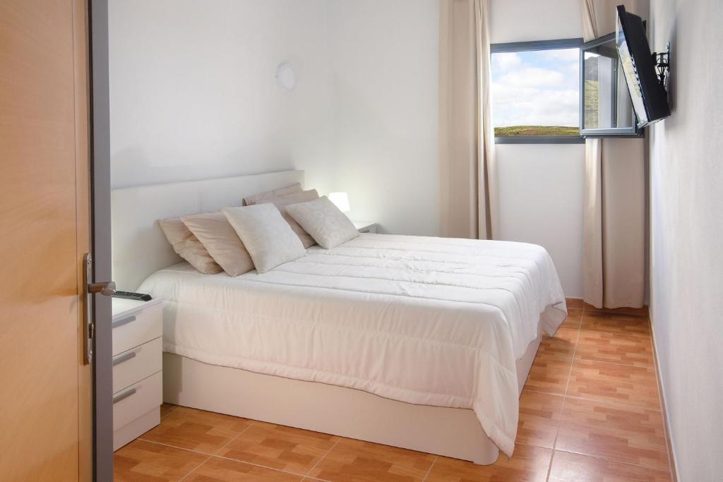 a white bedroom with a white bed and a window at Apartamento Ye in Haría
